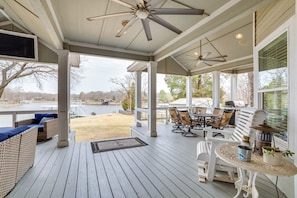 A covered outdoor patio with a ceiling fan, wicker furniture, a table with potted plants, and a view of a lake and trees. - Dock & Lake Access: Gem on Cedar Creek Reservoir (Mabank)