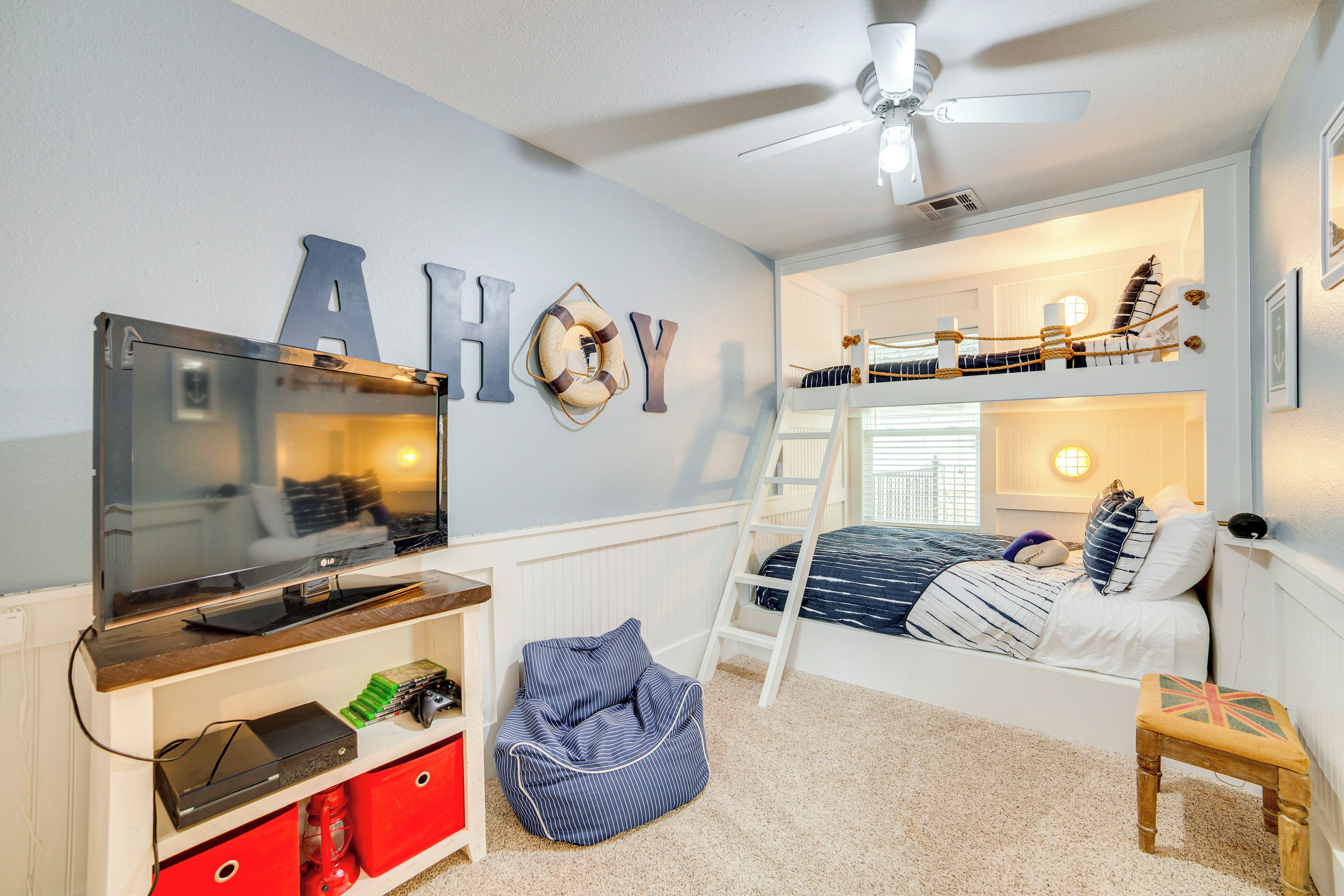 A child's bedroom with bunk beds, a TV, and a ceiling fan.
