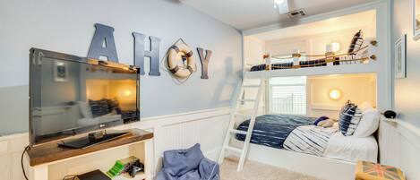 A child's bedroom with bunk beds, a TV, and a ceiling fan.