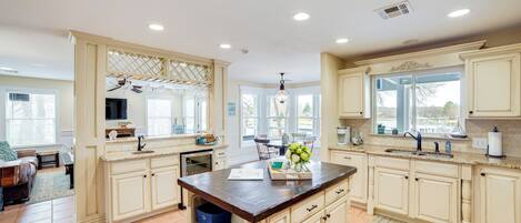 A spacious kitchen with white cabinetry, a central island, and a dining area with a table and chairs.
