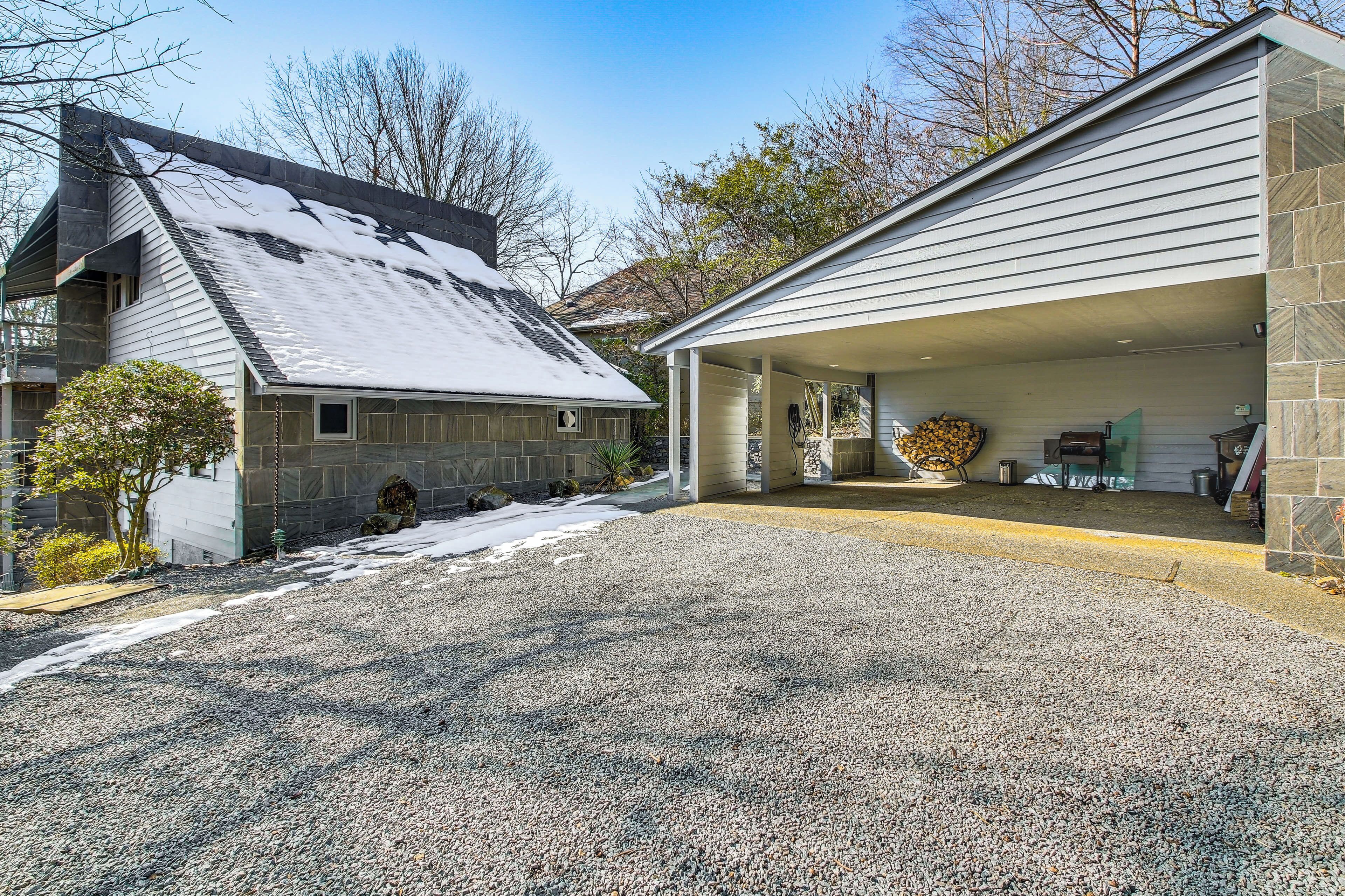 A two-story house with a covered garage and a gravel driveway.