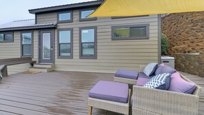 Une terrasse extérieure couverte, aménagée avec des meubles en osier et dotée d’un mur en pierre.