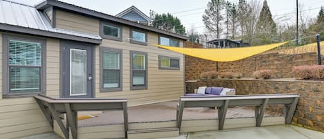A house with a patio, a yellow shade sail, and a stone wall.