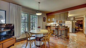 A kitchen with a round table, chairs, a refrigerator, and wooden cabinets.