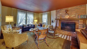 A cozy living room with a fireplace, comfortable seating, and a bookshelf.