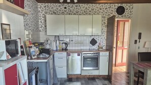 A kitchen with white cabinets, a microwave, a stove, and a sink. - Vacation apartment Puth (Koblenz)