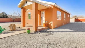 A single-story house with a porch, a front door, and a small garden area with a cactus and a potted plant. - 3 Mi to Elephant Butte Lake: Cozy Retreat! (Truth or Consequences)
