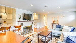 A modern kitchen with white cabinetry, a flat-screen TV, and a fireplace.