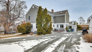 A two-story house with a gravel driveway and snow on the ground.