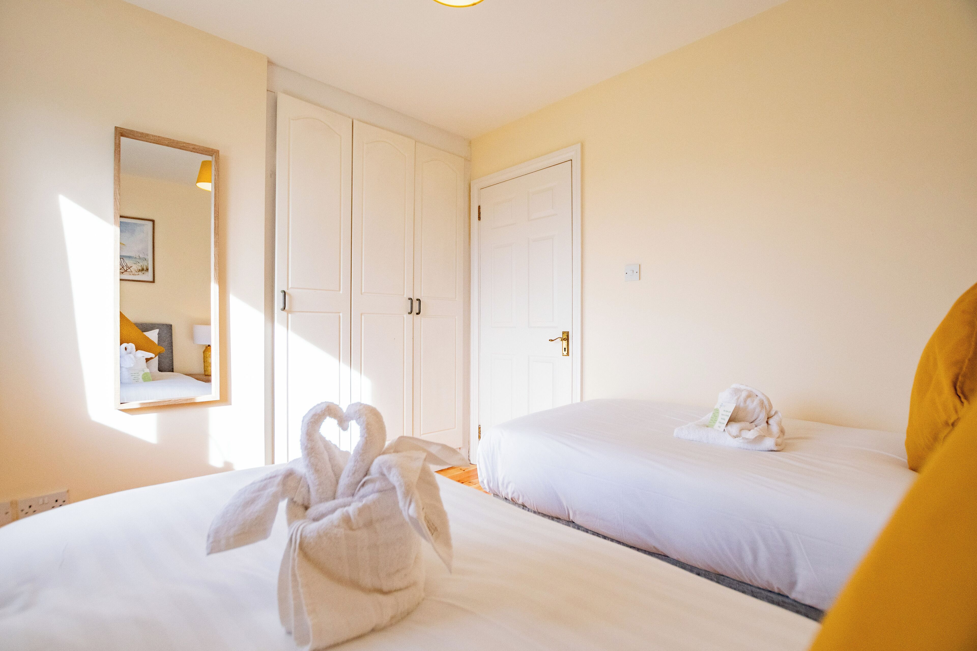 Une chambre d’hôtel avec deux lits, une armoire et un miroir.