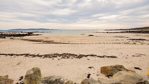 Ein Strand mit felsigem Ufer und ruhigem Wasser im Hintergrund.