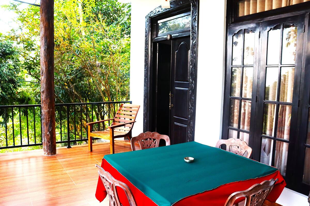 A room with a billiards table, two chairs, a wooden bench, and a black door.