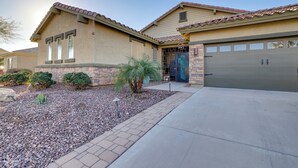 A residential house with a garage, a stone facade, and a small garden with a palm tree. - Putting Green & Hot Tub: Goodyear Retreat! (Goodyear)