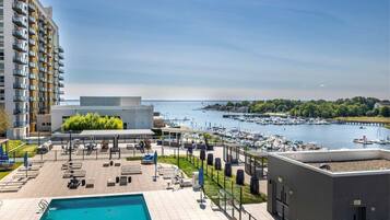 A rooftop pool area with lounge chairs, a swimming pool, and a view of a marina with boats.
