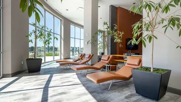 A modern waiting area with sun loungers, large windows, and indoor plants.