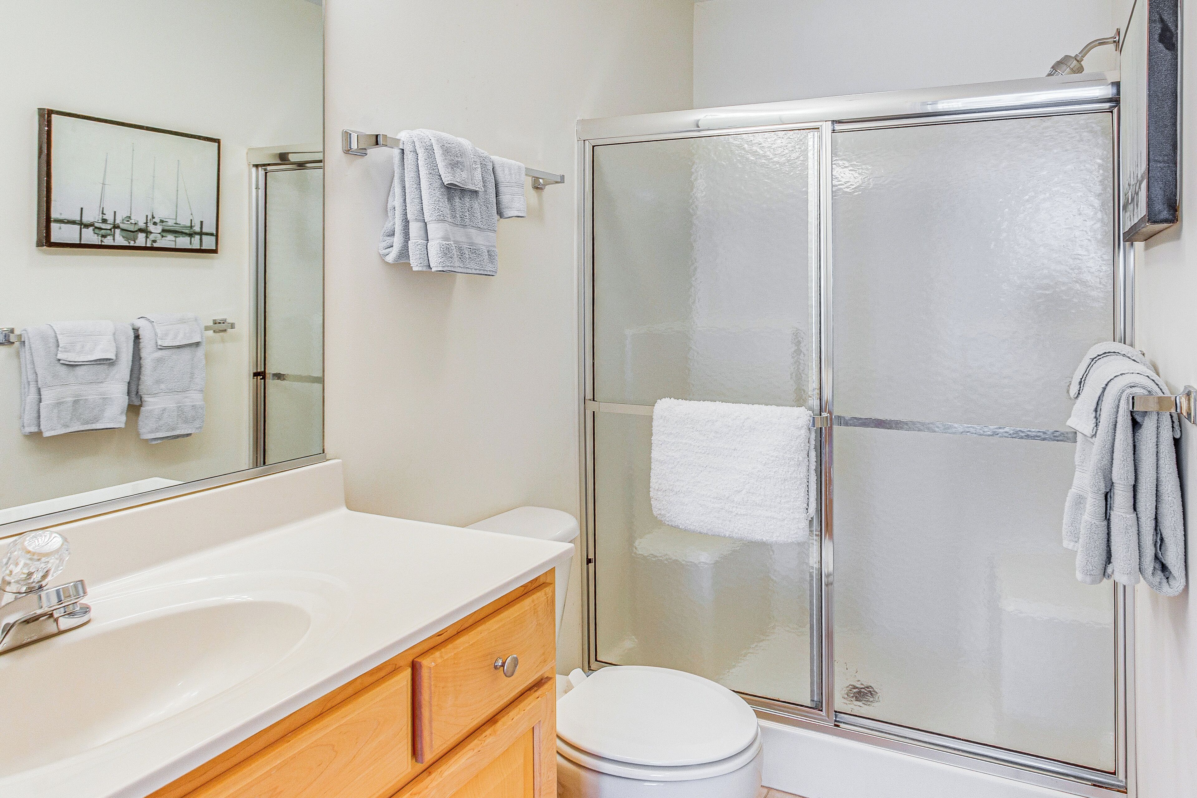 Une salle de bain avec une douche à parois de verre, un lavabo blanc et des toilettes.