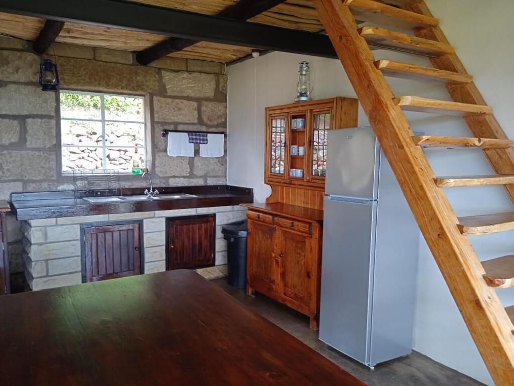 A rustic kitchen with a wooden table, a refrigerator, a wooden cabinet, and a wooden ladder.