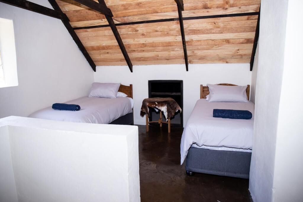 A small, cozy room with two beds, a fireplace, and a sloped ceiling.