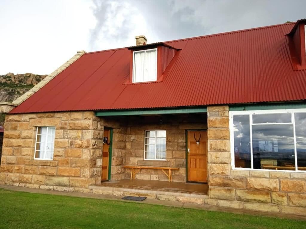Un edificio de piedra con techo rojo, una banca de madera afuera y una puerta adornada con cuernos de ciervo.