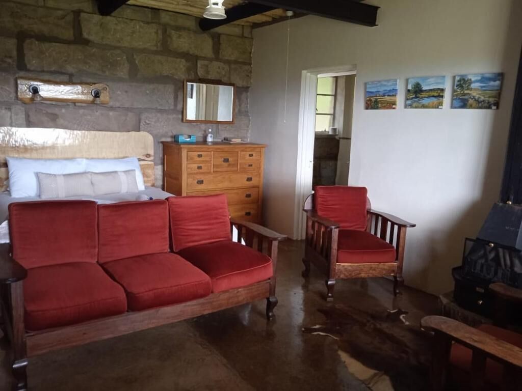 A cozy room with a wooden bed, a red sofa, a wooden dresser, and a fireplace.