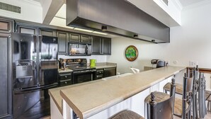 A modern kitchen with stainless steel appliances, a large island, and a decorative wall piece. - Mtn-view Condo w/ Pool Access in Palm Springs! (Palm Springs)