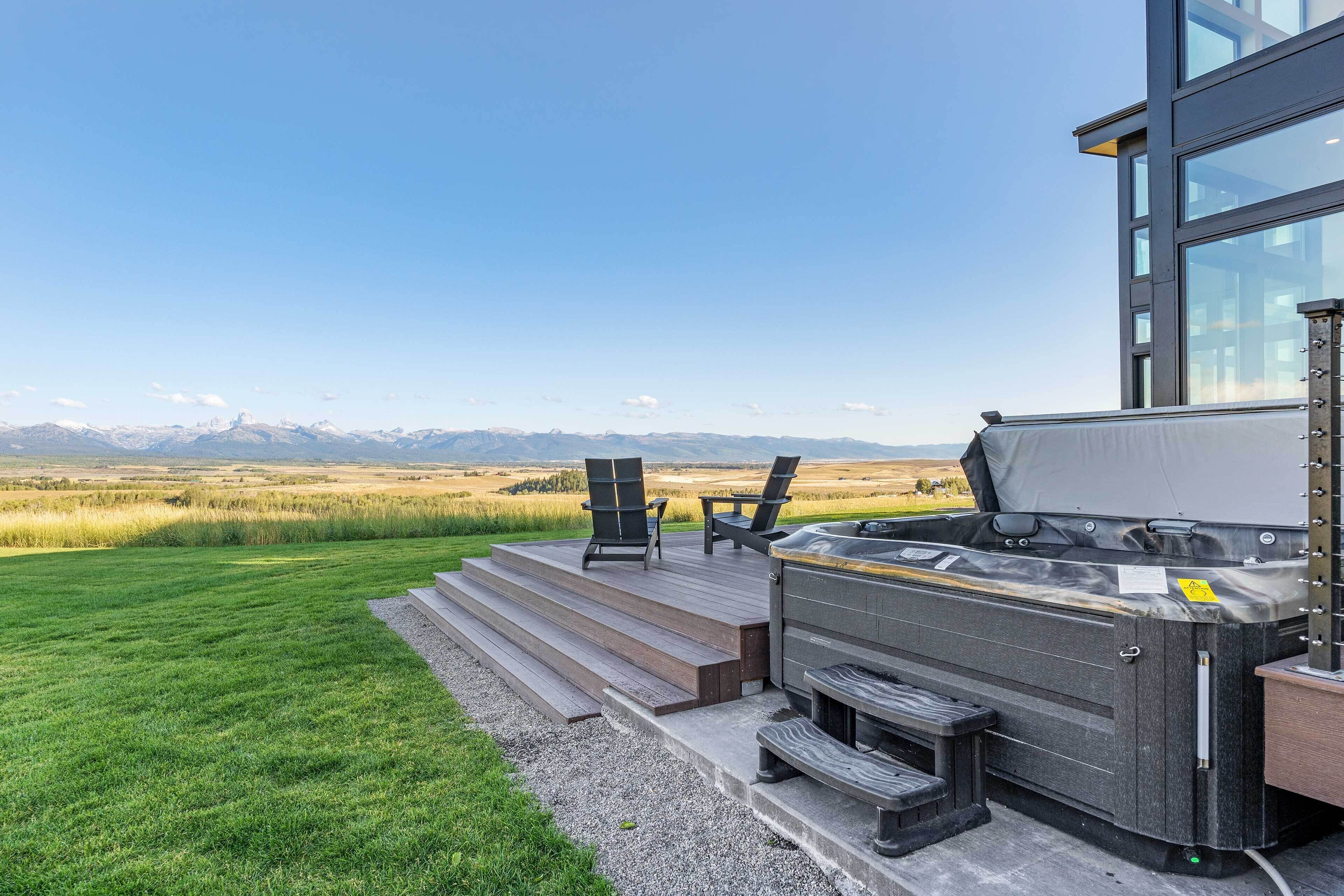 A hot tub on a wooden deck with a view of mountains.