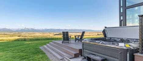 A hot tub on a wooden deck with a view of mountains.