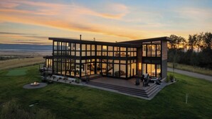 A modern two-story house with large glass windows, a covered outdoor seating area, and a well-maintained lawn. - Hot Tub, 23 Mi to Grand Targhee: Luxe Retreat (Tetonia)