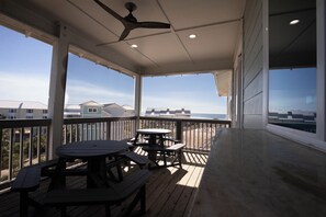 En overdækket terrasse med picnicborde og en loftsvifte.