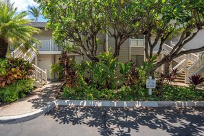 A residential building with a covered outdoor area, a staircase, and a sign indicating the number of units.
