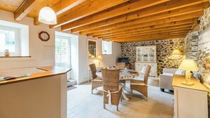 Un interior acogedor con techo de madera, paredes de piedra, mobiliario de mimbre y chimenea de piedra.