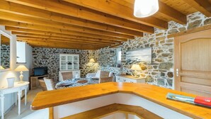 Un interior acogedor con paredes de piedra, vigas de madera, una barra de madera y un televisor.