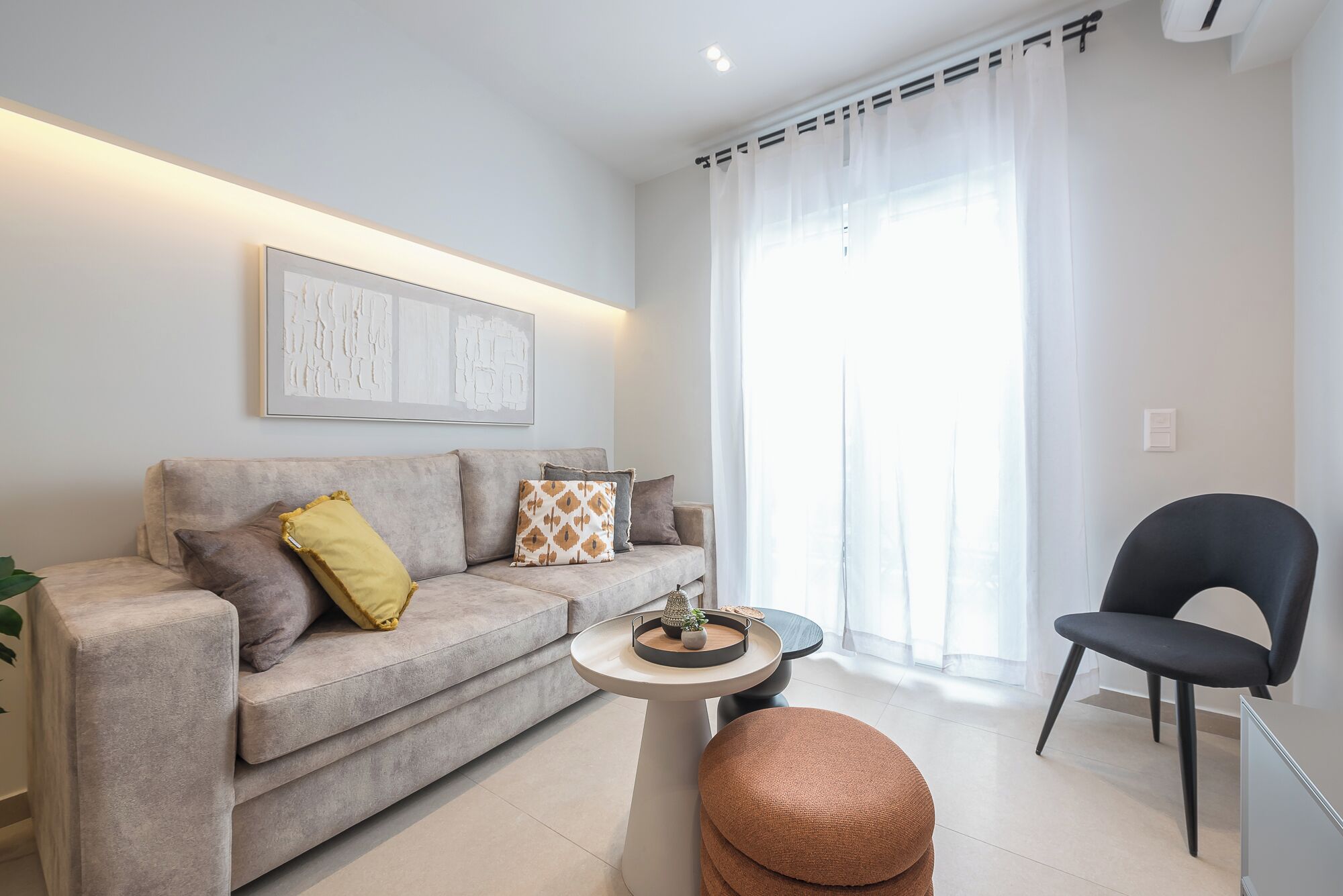 A modern living room with a grey sofa, a round coffee table, and a black chair.