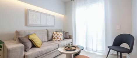 A modern living room with a grey sofa, a round coffee table, and a black chair.