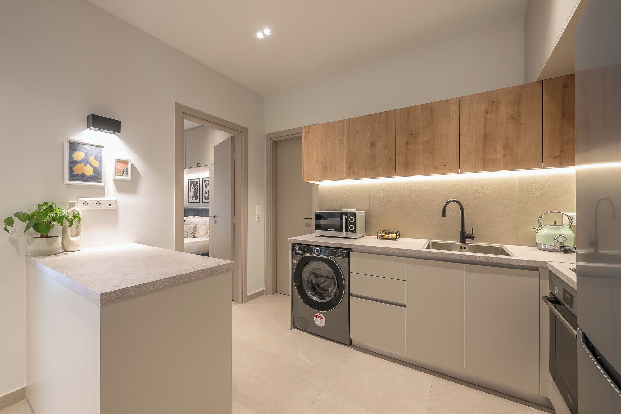 A modern kitchen with a built-in washing machine, a microwave, and a kettle.