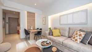 Ein modernes Wohnzimmer mit grauem Sofa, Couchtisch und Essbereich mit Holztisch und Stühlen.