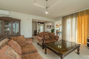 A living room with a sofa, armchair, and a glass-top coffee table.