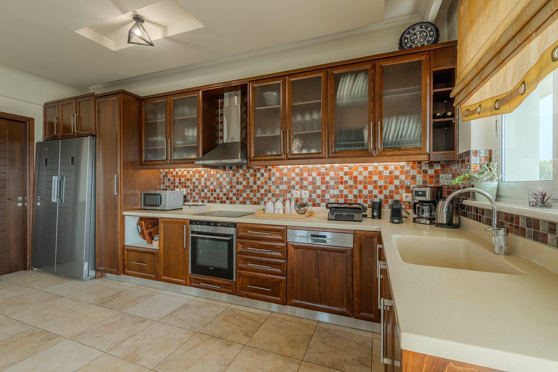 A modern kitchen with wooden cabinets, a stainless steel refrigerator, a microwave, and a coffee maker.