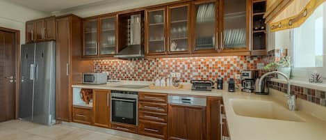 A modern kitchen with wooden cabinets, a stainless steel refrigerator, a microwave, and a coffee maker.