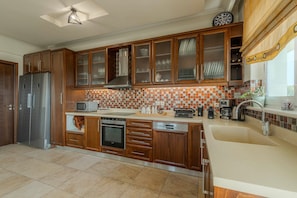 A modern kitchen with wooden cabinets, a stainless steel refrigerator, a microwave, and a coffee maker.