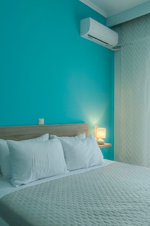 Ein Hotelzimmer mit einem Bett, einem Nachttisch, einer Lampe und einer Klimaanlage.