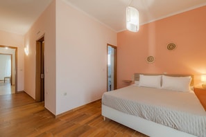Een slaapkamer met een bed, nachtkastje en een hanglamp.