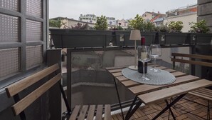 A rooftop terrace with a table set for two, a chair, and a potted plant. - Brand new 2 BR With Balcony in Sempione (Milan)