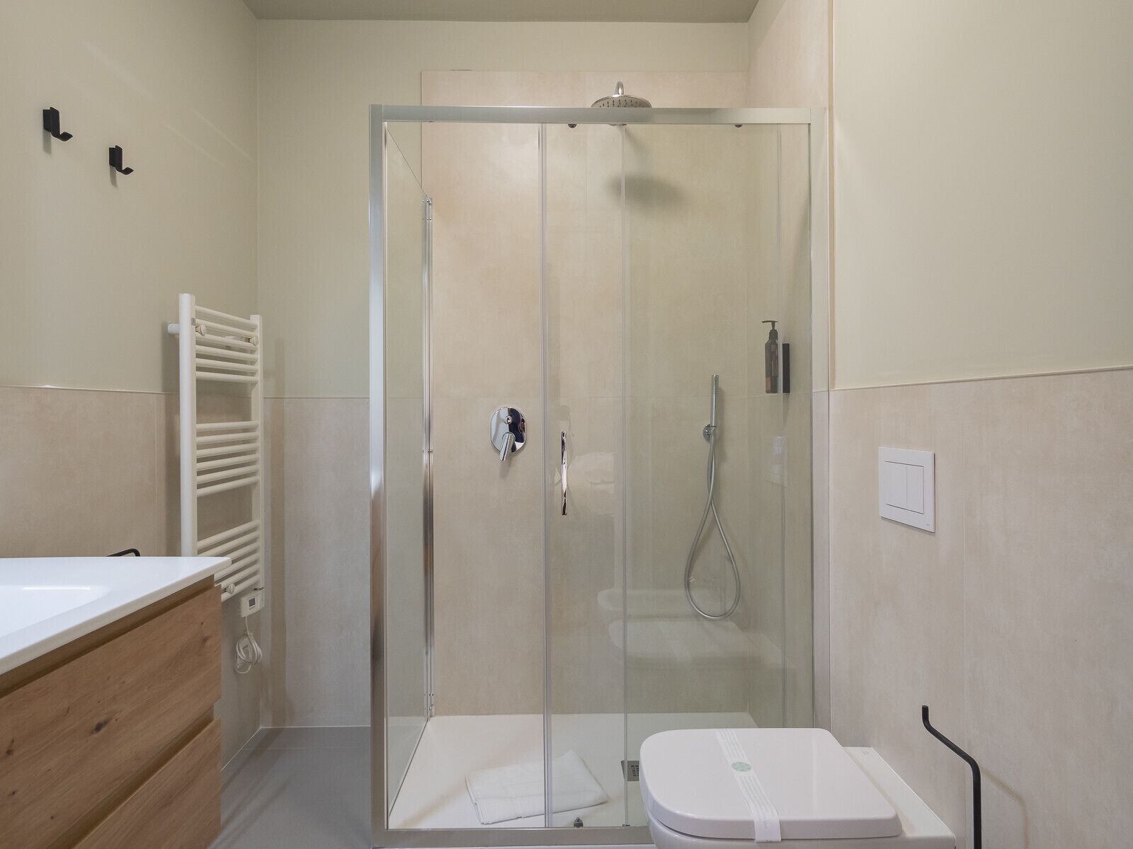 Une salle de bain moderne avec une douche à parois de verre, des toilettes blanches et un meuble-lavabo en bois avec un évier.