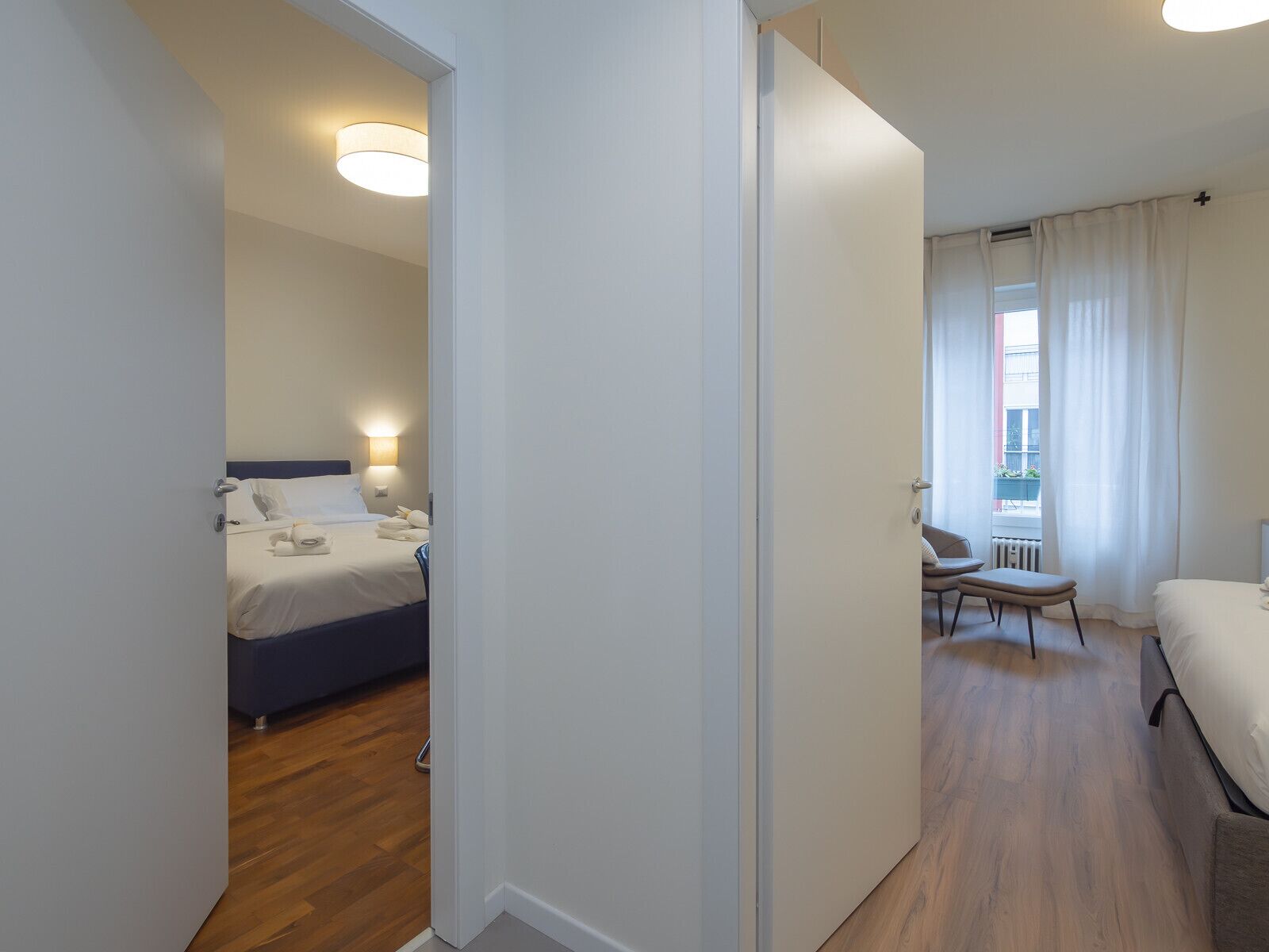 A hotel room with a bed, bedside table, and a chair.