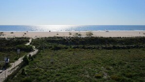 En strand med klart skint, sandet bredde og en sti, der fører ned til stranden.