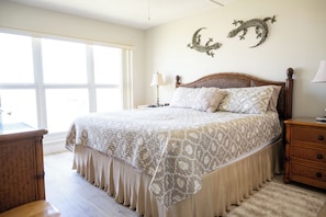 A bedroom with a large bed, a nightstand, a dresser, and a window.