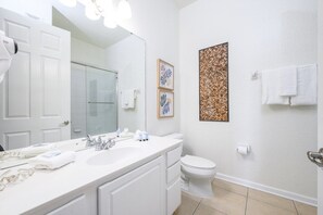 A modern bathroom with a white vanity, a large mirror, a toilet, and a shower area. - Pool View Penthouse 3 Bedroom Condo (Orlando)