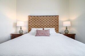 A neatly made bed with white bedding and a patterned pillow, flanked by two bedside tables with lamps. - Pool View Penthouse 3 Bedroom Condo (Orlando)