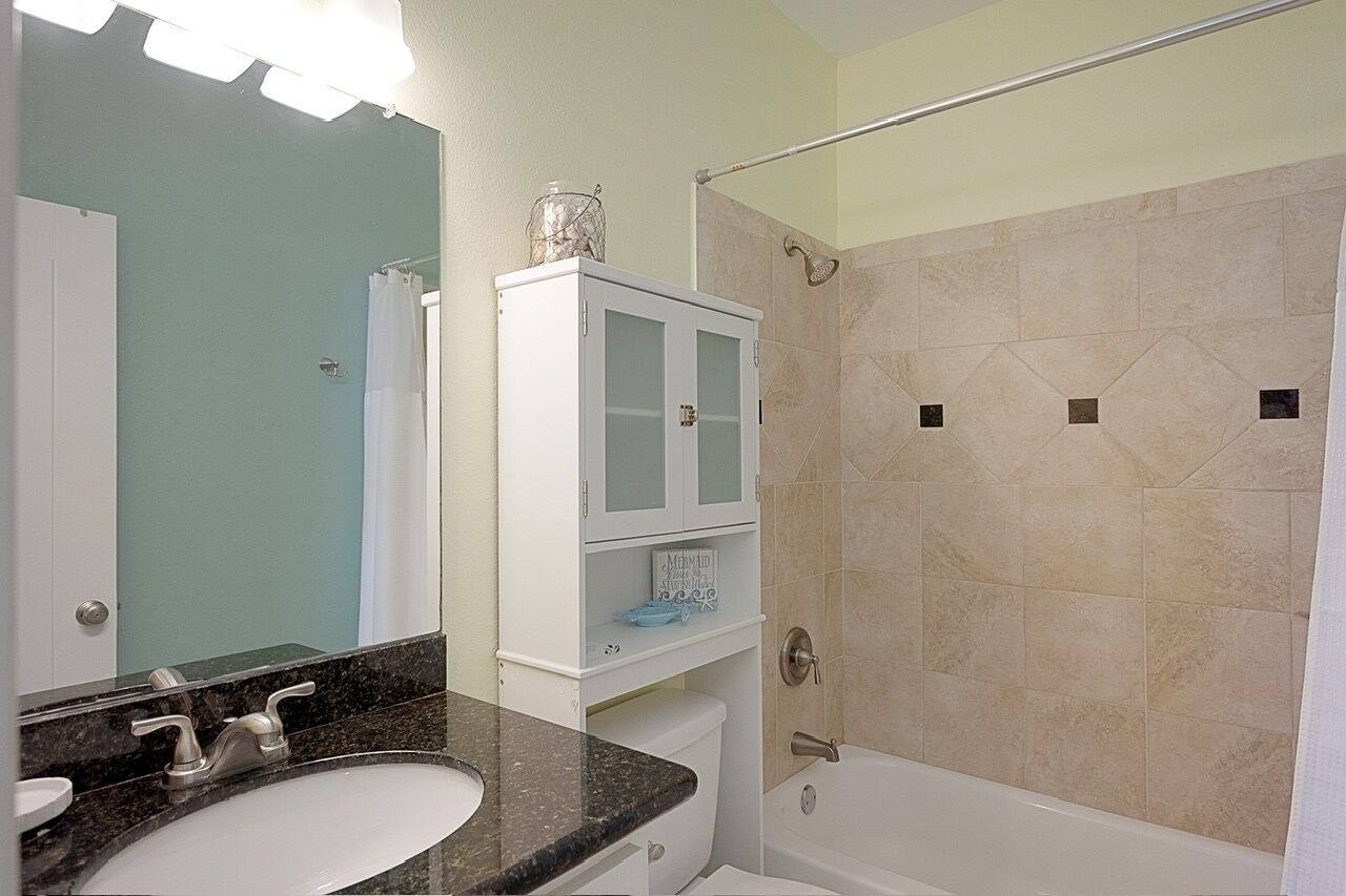 Une salle de bain équipée d’un lavabo, d’un miroir, d’un meuble de rangement et d’une zone douche.